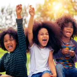 Happy African American boy and girl kids group playing in the playground in school. Children friendship and education concept.